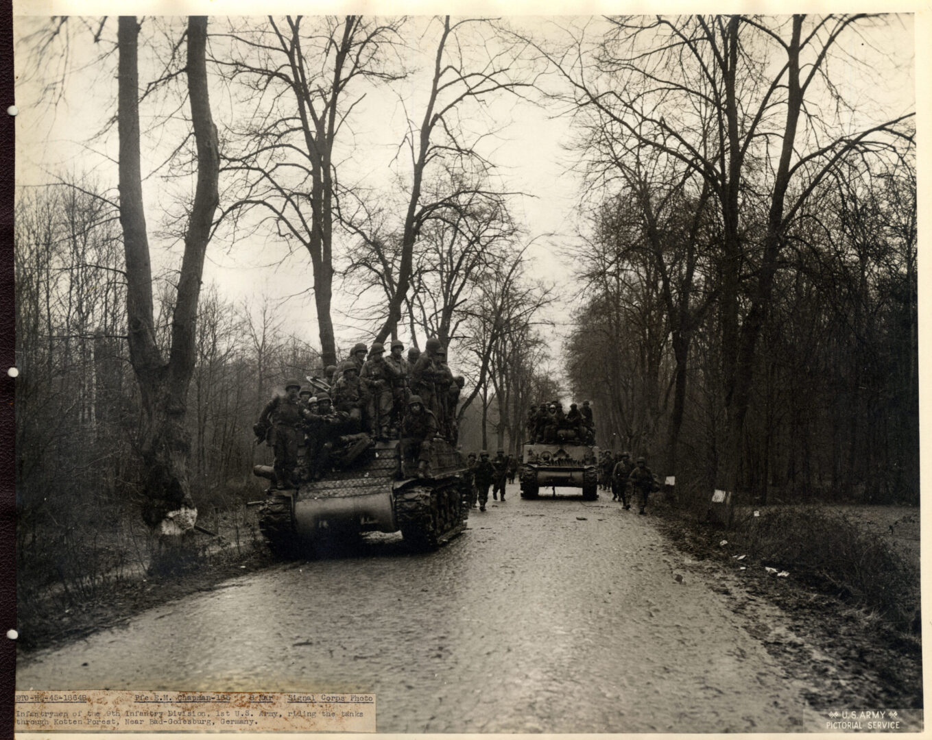 Infantrymen riding their tanks through Kotten Forest