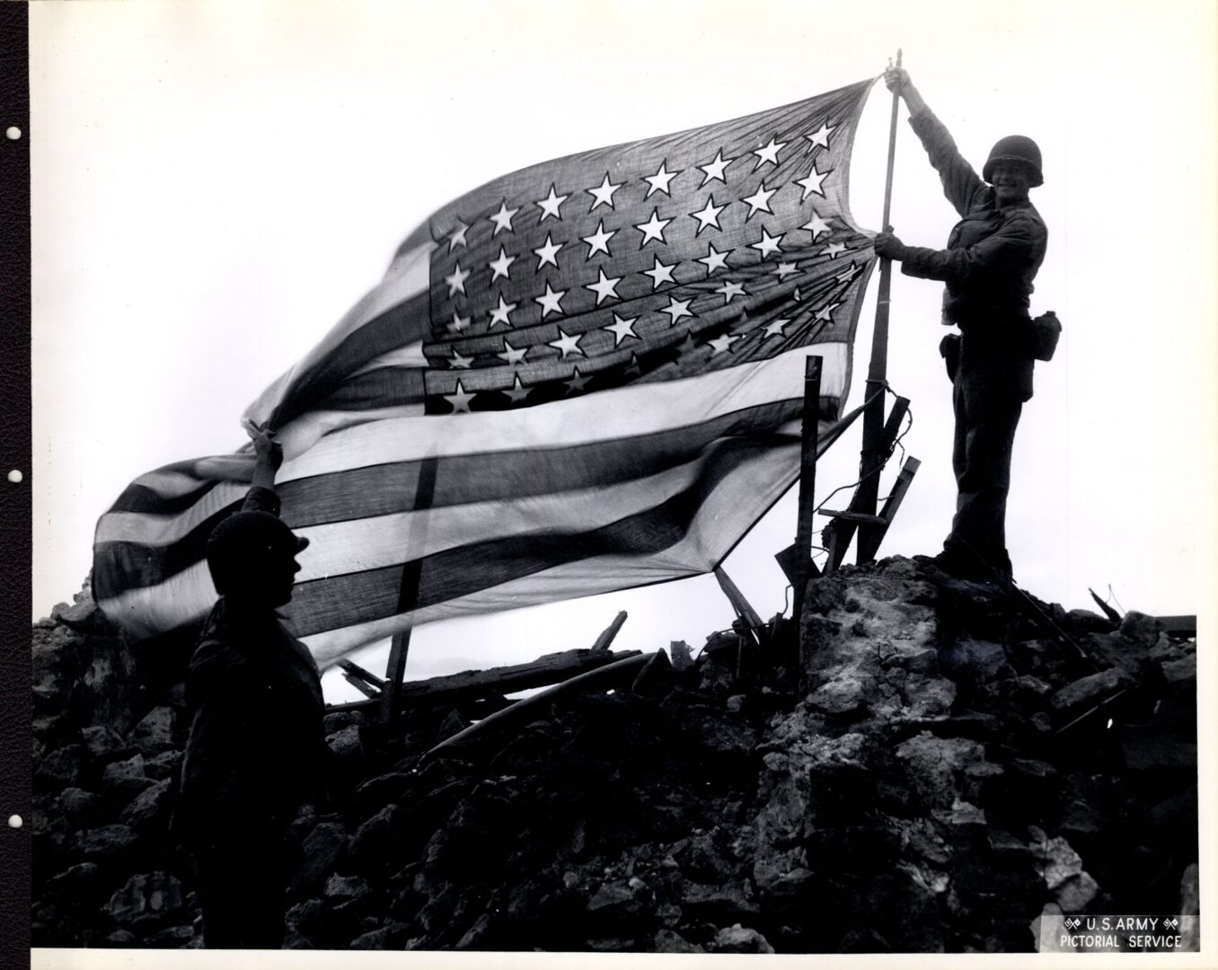 Two American soldiers holding up the American flag