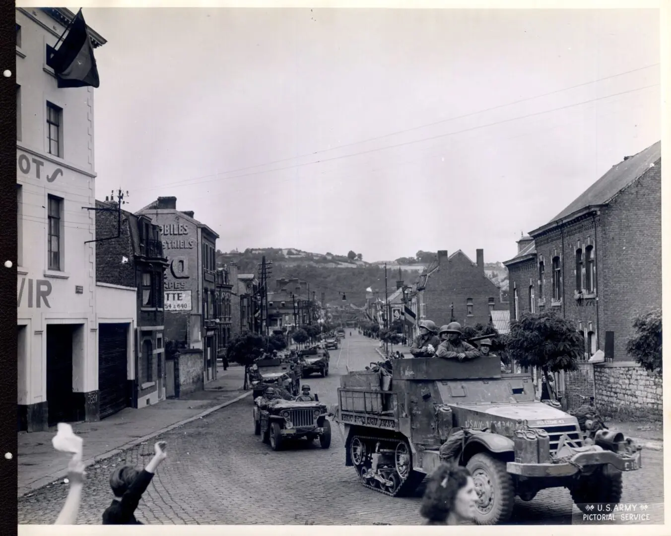 Jeeps and half trucks pass through a town in Belgium