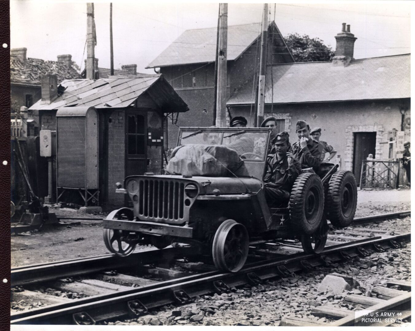 Soldiers ride a jeep altered to travel on the railroad