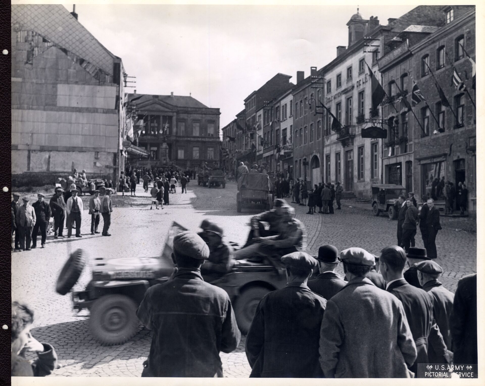 Belgians line up on the street as American soldiers pass by